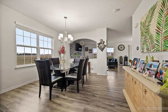 dining space with arched walkways, a notable chandelier, baseboards, and dark wood-style floors
