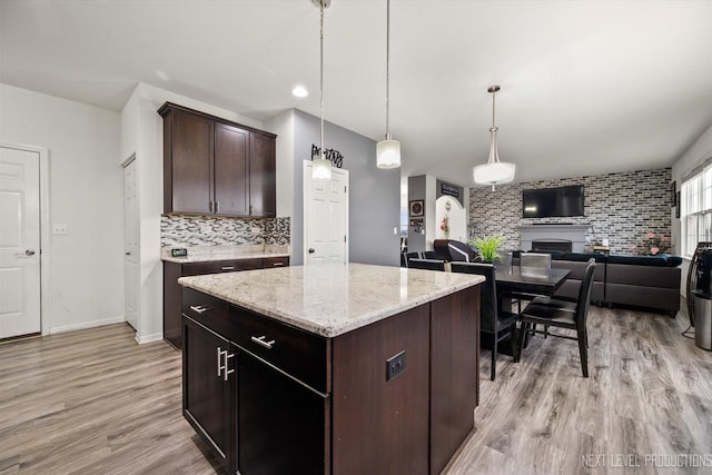 kitchen featuring light wood-style flooring, dark brown cabinets, backsplash, and hanging light fixtures