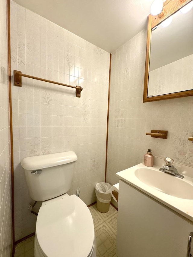 half bath with tile walls, vanity, and toilet