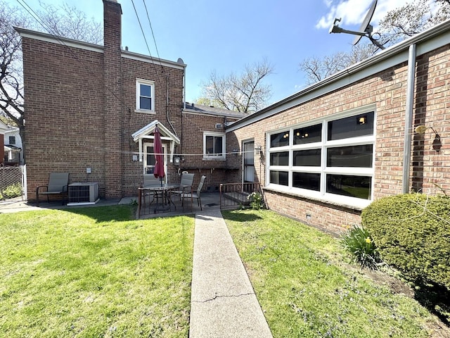 back of property with a chimney, central AC unit, a yard, a patio, and brick siding