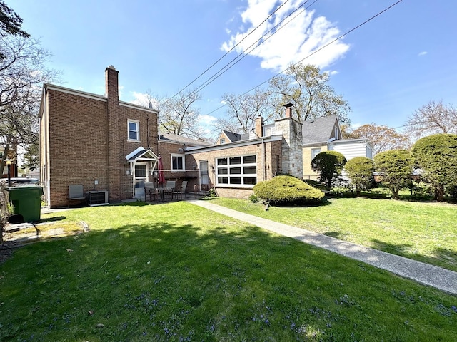 rear view of property featuring a yard, a patio, a chimney, and central AC unit