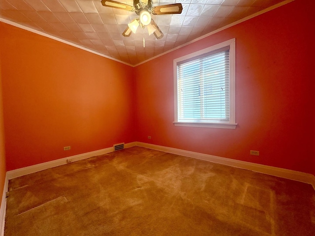 empty room featuring a ceiling fan, visible vents, carpet floors, and ornamental molding