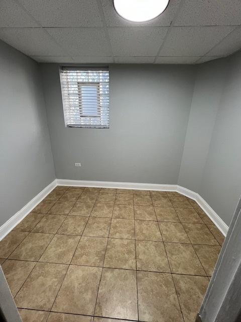tiled spare room with baseboards and a drop ceiling