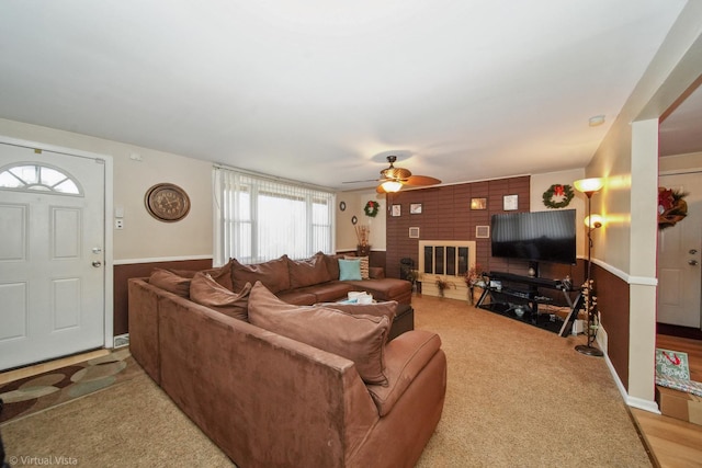 living area featuring ceiling fan and a brick fireplace