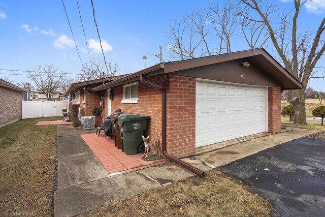 view of side of property with brick siding, driveway, and fence