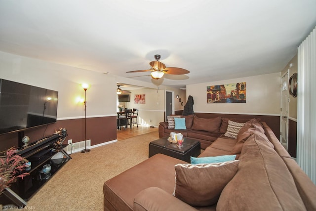 living area featuring a ceiling fan and carpet