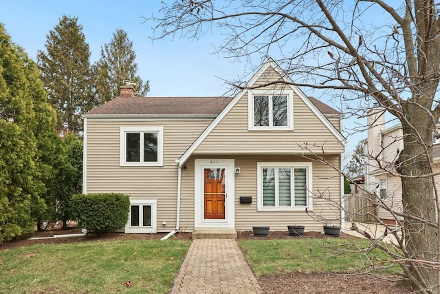 view of front of house featuring a chimney, a shingled roof, and a front lawn