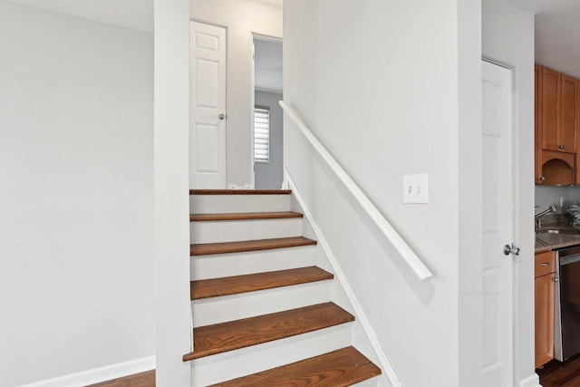 staircase featuring baseboards and wood finished floors