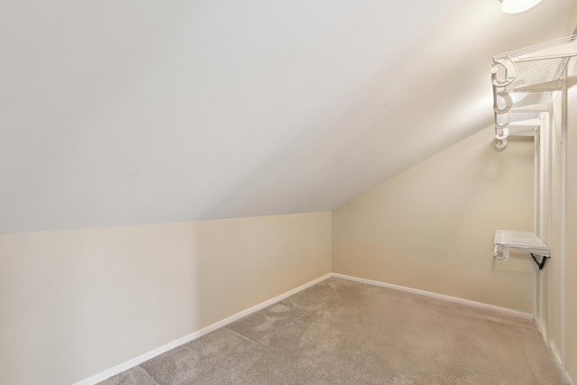 additional living space with baseboards, light colored carpet, and vaulted ceiling