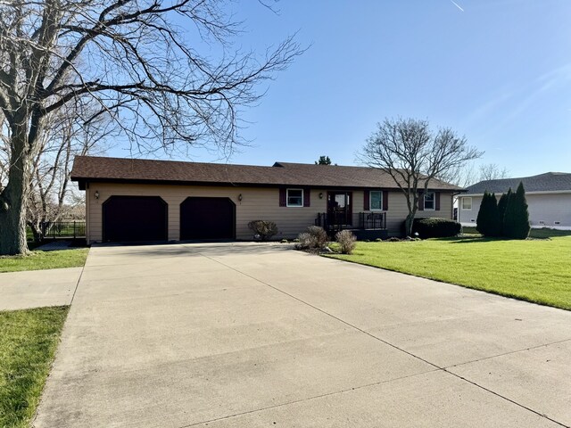 ranch-style house featuring a garage, a front lawn, and concrete driveway