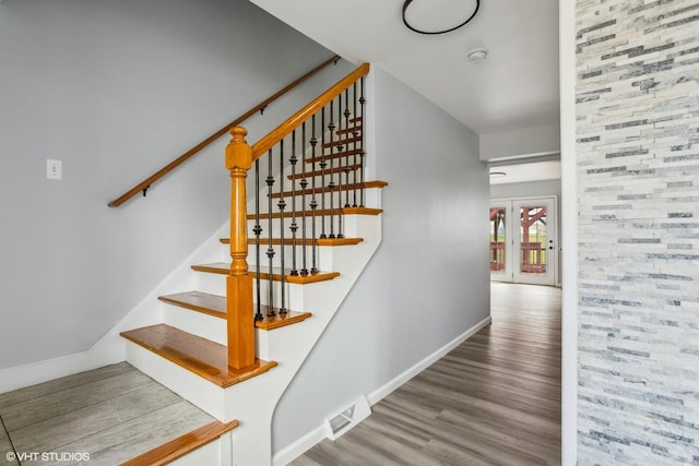stairs with visible vents, baseboards, and wood finished floors