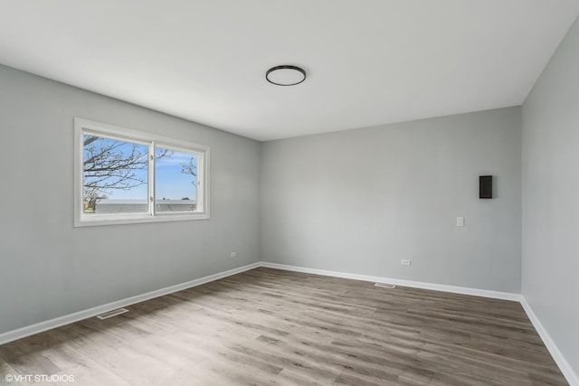 spare room with visible vents, baseboards, and wood finished floors