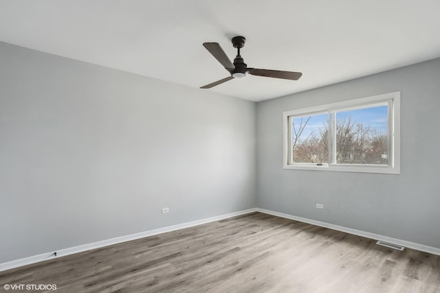 spare room featuring ceiling fan, visible vents, baseboards, and wood finished floors