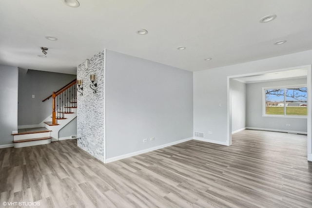 unfurnished living room featuring visible vents, baseboards, and wood finished floors