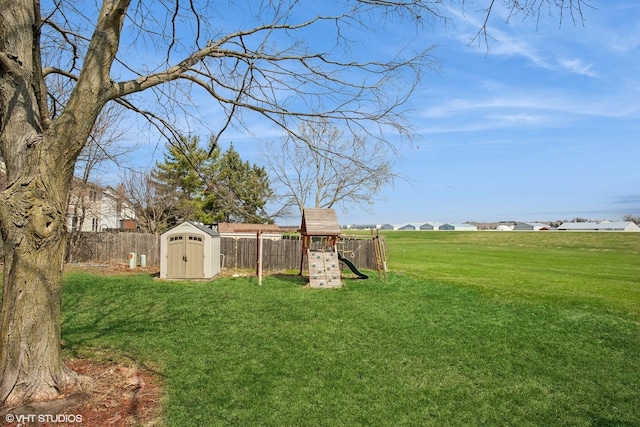 view of yard featuring a fenced backyard, a storage shed, an outdoor structure, and a playground