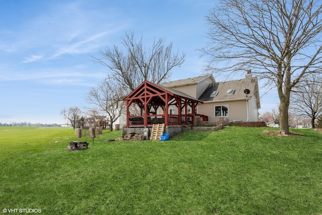 rear view of property featuring a gazebo, a yard, and a chimney