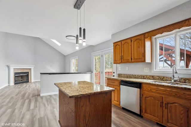 kitchen with vaulted ceiling with skylight, dishwasher, a sink, light wood-style floors, and a kitchen island