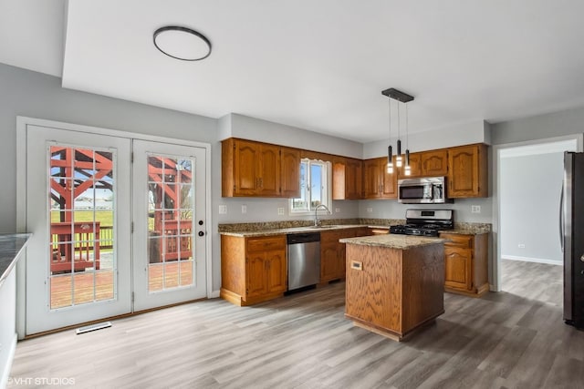 kitchen with a center island, brown cabinets, wood finished floors, and stainless steel appliances