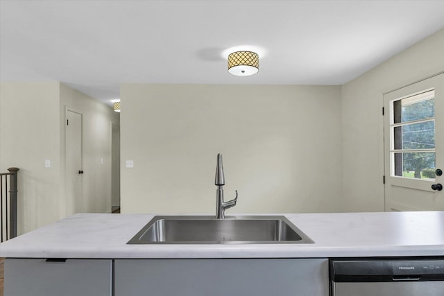 kitchen featuring light countertops, dishwasher, and a sink