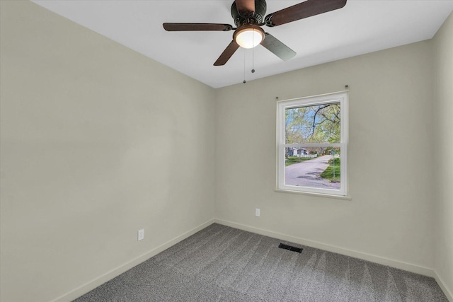 spare room featuring dark carpet, visible vents, a ceiling fan, and baseboards