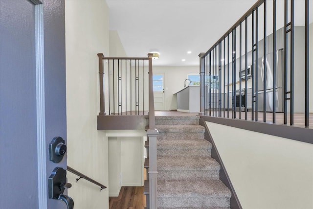 staircase with baseboards, wood finished floors, and recessed lighting