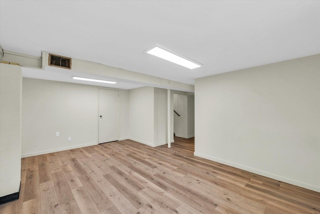finished basement featuring baseboards, visible vents, and light wood-type flooring