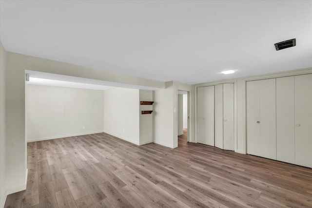 finished basement with baseboards, wood finished floors, and visible vents