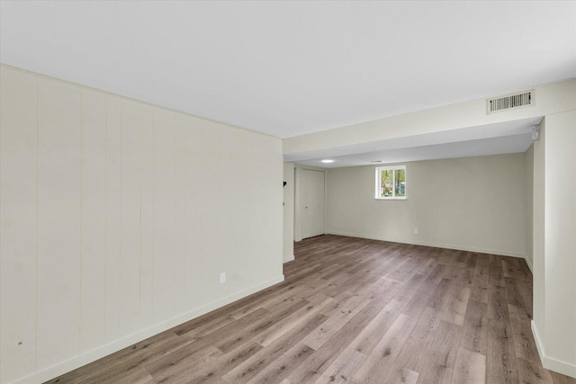 basement featuring wood finished floors, visible vents, and baseboards