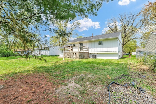 rear view of property with a deck, board and batten siding, fence, a yard, and cooling unit