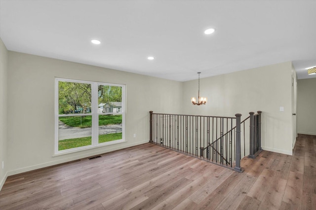 interior space featuring wood finished floors, visible vents, an inviting chandelier, and an upstairs landing