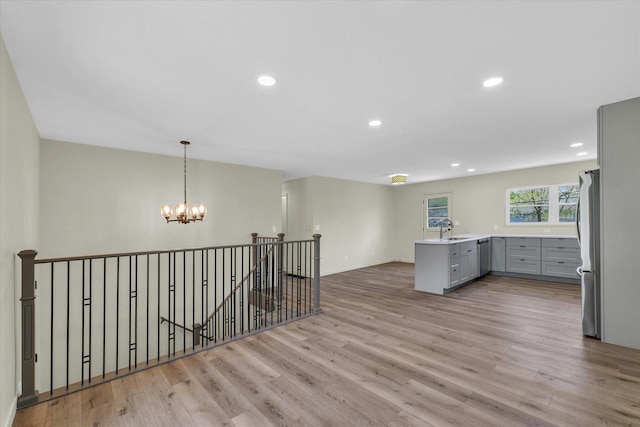 kitchen featuring a sink, light wood-style floors, gray cabinets, stainless steel appliances, and a notable chandelier