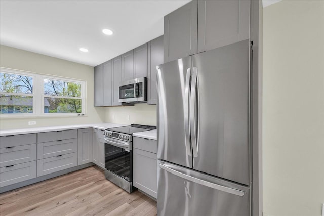 kitchen with stainless steel appliances, recessed lighting, light wood-style floors, gray cabinets, and light countertops