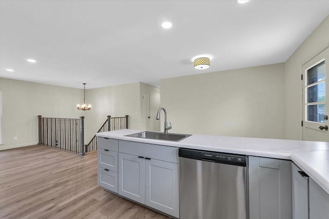kitchen featuring stainless steel dishwasher, a sink, light wood finished floors, and light countertops