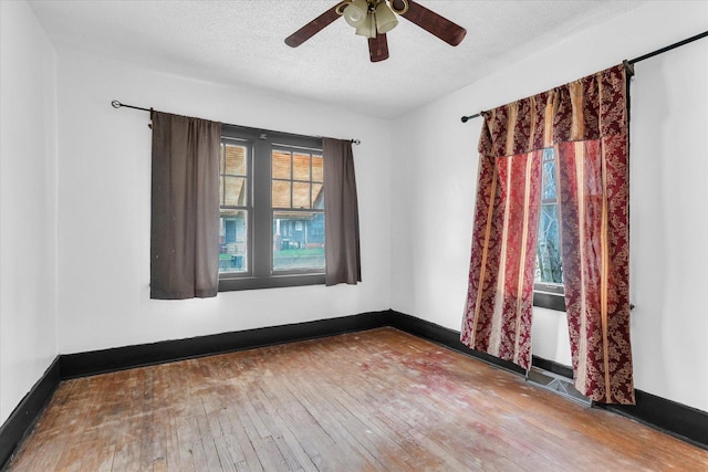 unfurnished room with wood-type flooring, a textured ceiling, baseboards, and ceiling fan