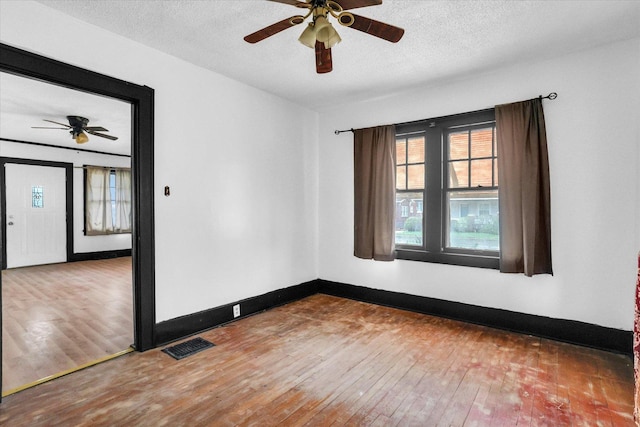 unfurnished room featuring a ceiling fan, visible vents, a textured ceiling, and wood-type flooring
