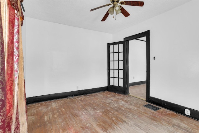 spare room with baseboards, visible vents, ceiling fan, and wood-type flooring