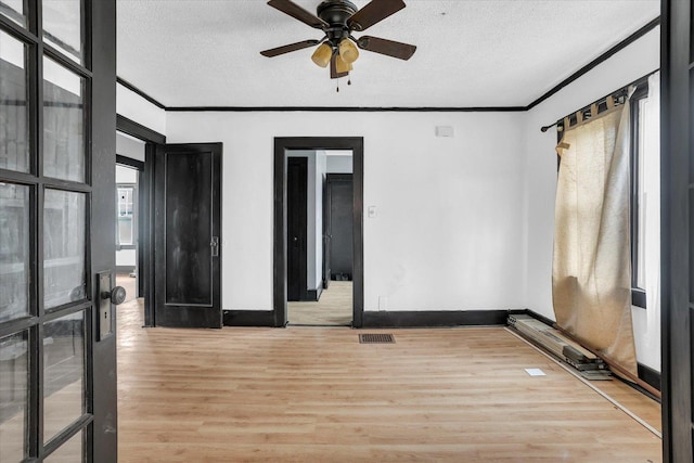 empty room with ceiling fan, light wood finished floors, a textured ceiling, and visible vents