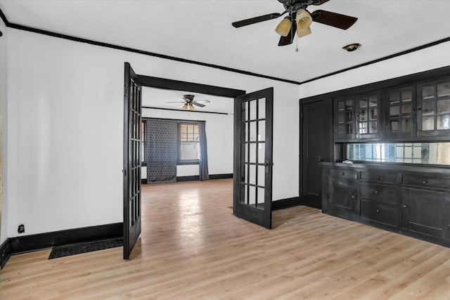 interior space featuring french doors, a textured ceiling, light wood-style floors, a ceiling fan, and ornamental molding