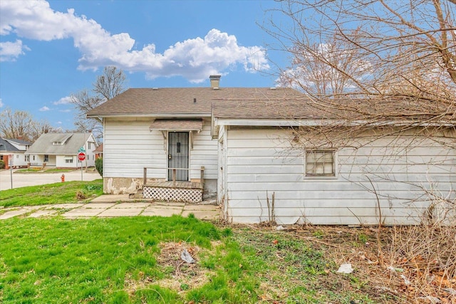 exterior space featuring roof with shingles and a front yard