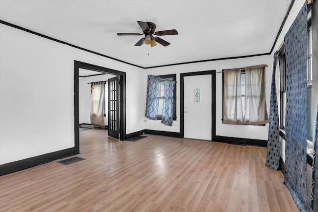 spare room featuring wood finished floors, visible vents, baseboards, a textured ceiling, and ceiling fan
