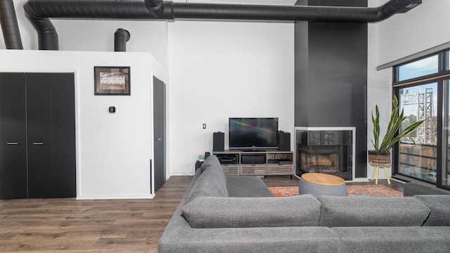 1760 W Wrightwood Ave Unit 305, Chicago, IL 60614 - living area featuring a tiled fireplace, wood finished floors, a towering ceiling, and baseboards