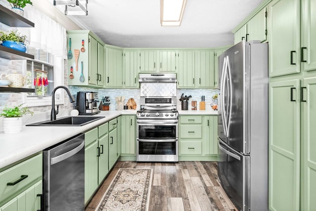 kitchen with backsplash, green cabinetry, appliances with stainless steel finishes, and a sink
