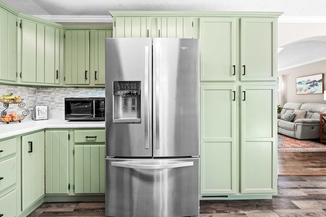 kitchen with arched walkways, stainless steel fridge, green cabinets, dark wood-type flooring, and ornamental molding