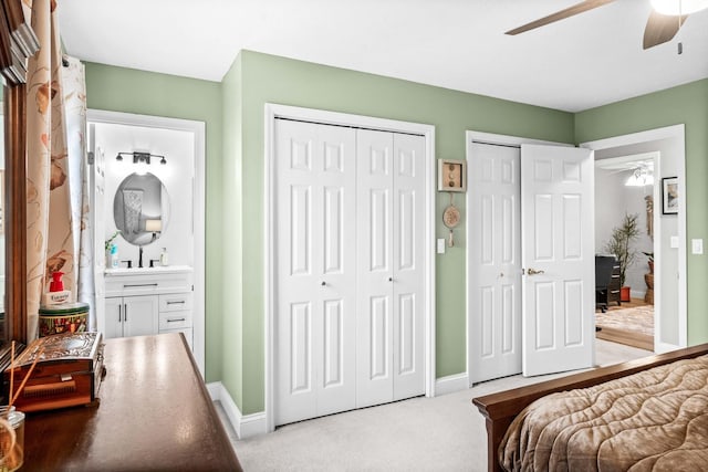 bedroom with multiple closets, a ceiling fan, baseboards, and light carpet