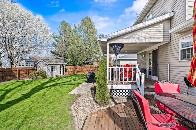 wooden deck with a fenced backyard, an outdoor structure, and a lawn