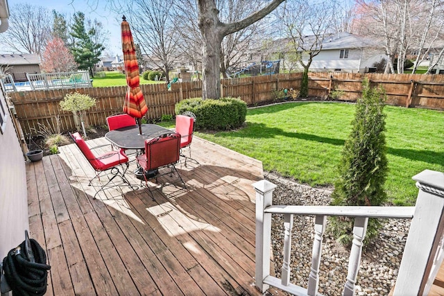 wooden deck featuring a fenced backyard, outdoor dining space, and a lawn