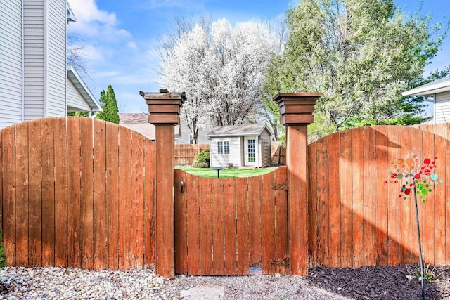 view of gate with fence and an outbuilding