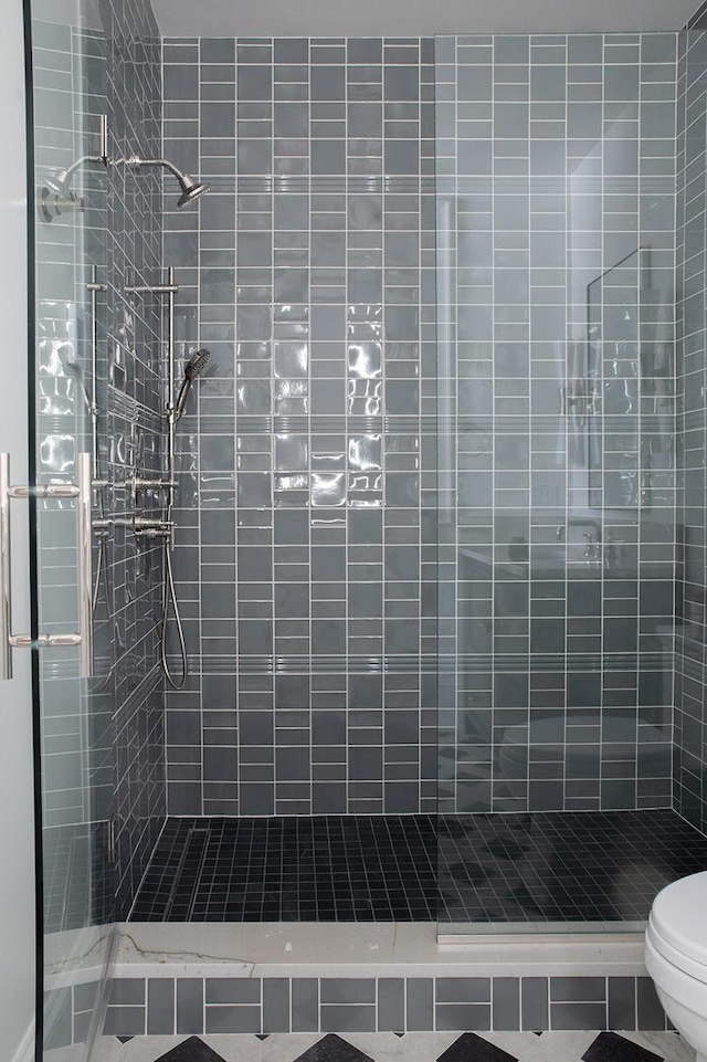 full bath featuring tiled shower and toilet