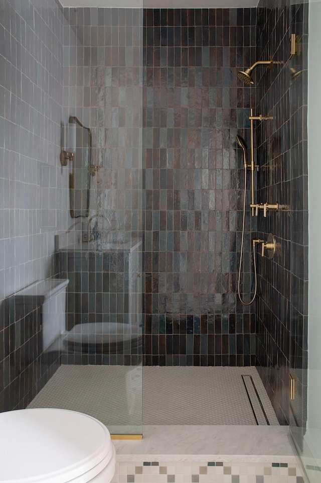 bathroom featuring a tile shower and toilet