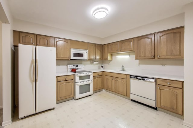 kitchen featuring a sink, light countertops, white appliances, brown cabinets, and light floors